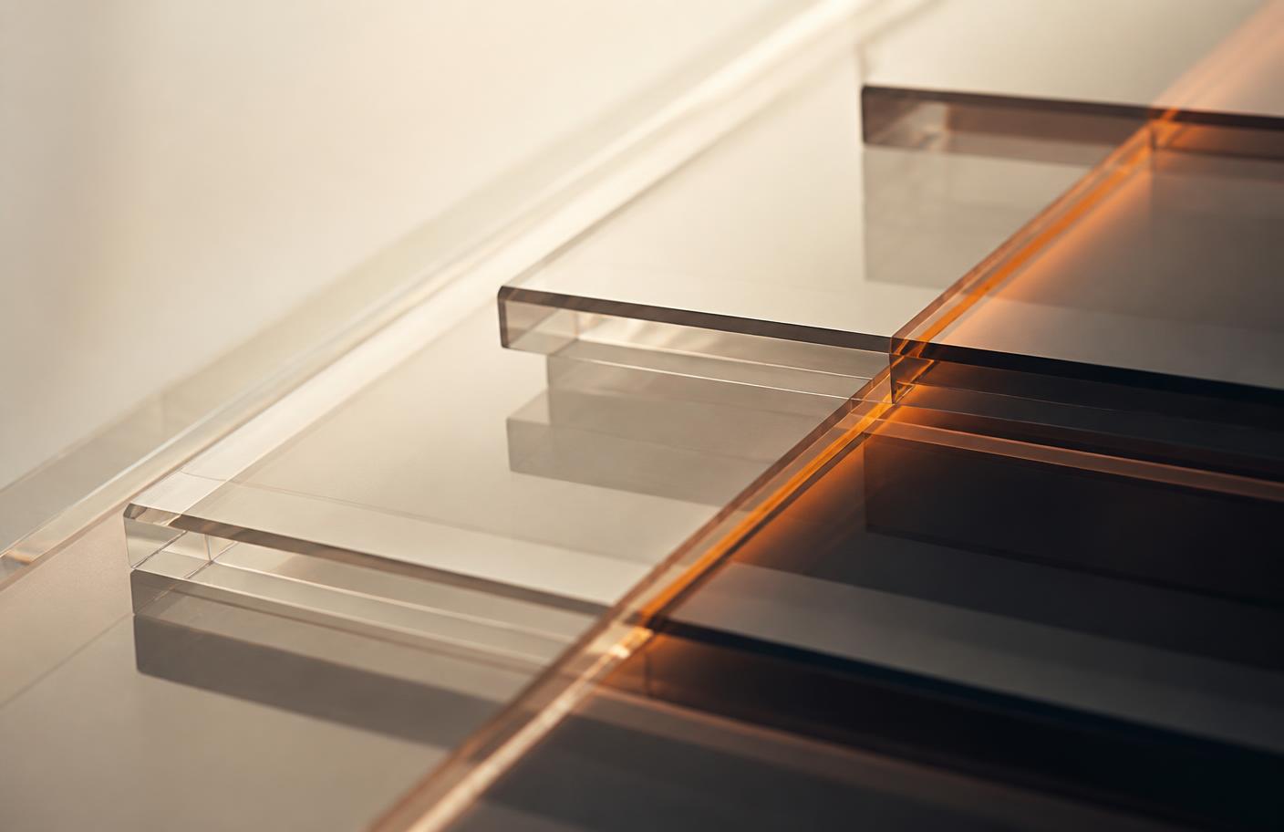 Layered translucent glass panels photographed in close-up with a warm orange highlight along one edge